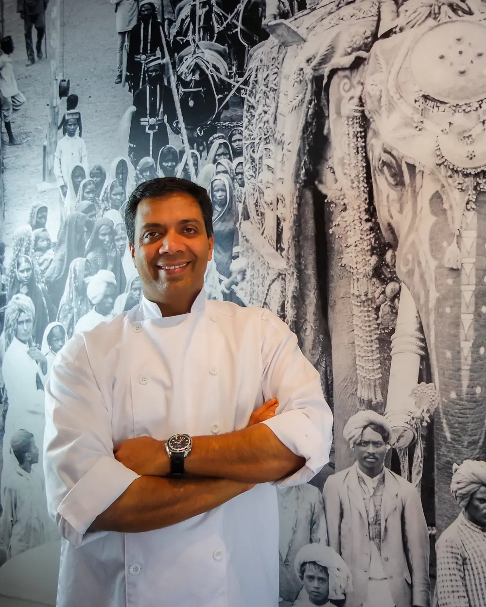 Chef Mohammed Sali in his whites, arms crossed, in front of the black-and-white elephant mural in the dining room.