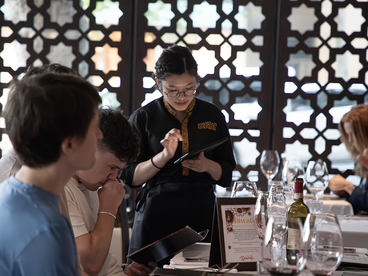 A Malabar server taking an order from guests at their table