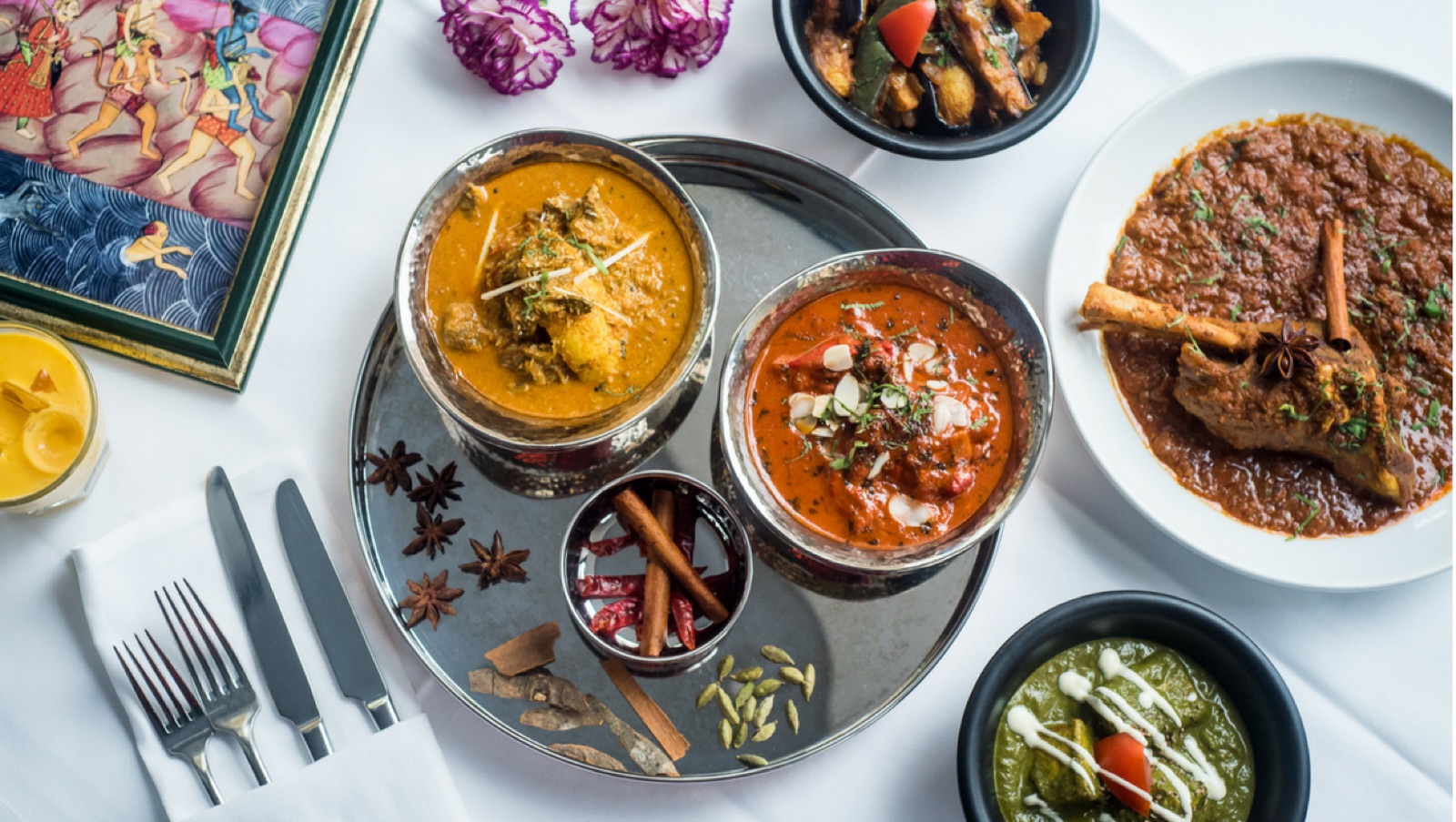 A shared spread of Malabar curries and sides on a steel platter, with whole spices, from above.