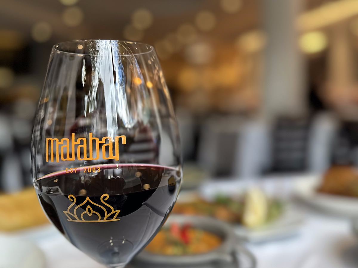 Red wine poured into a Riedel glass etched with the Malabar logo